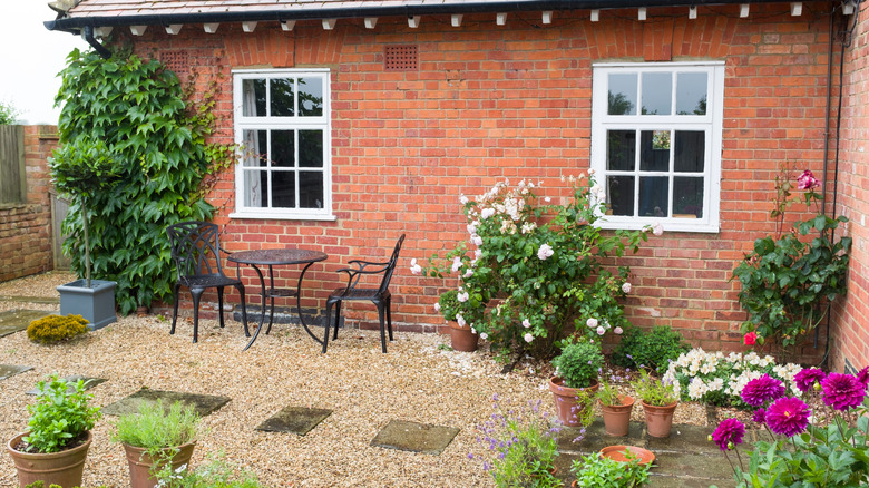 Çiçeklerle çevrili çakıl veranda üzerinde bistro masası