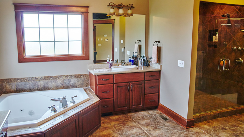 Kiraz ahşap dolap ve köşe küveti içeren bir banyo