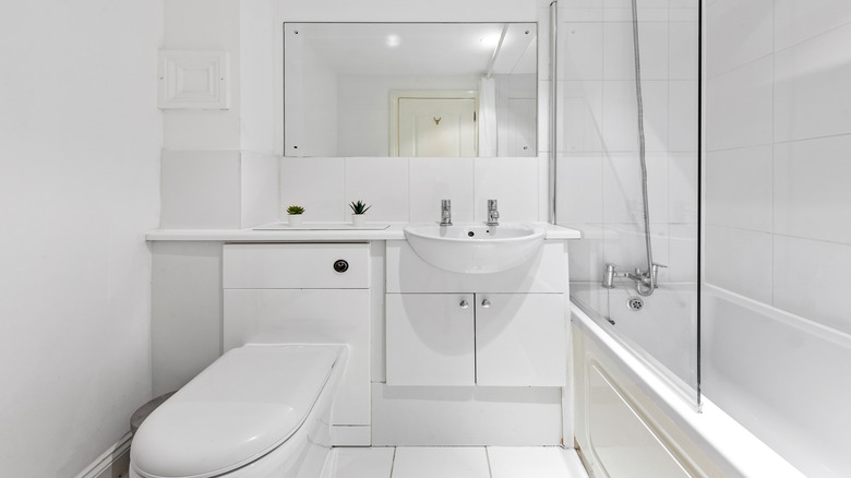 Tüm beyaz dolapları ve fayanslı bir banyo