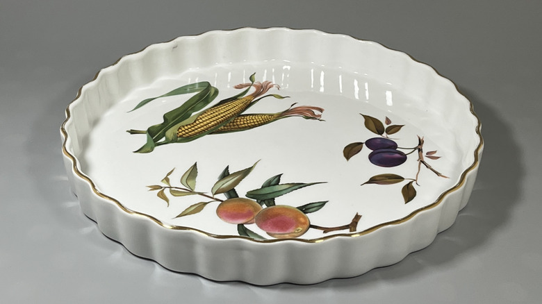 Kraliyet Worcester Evesham desenli Quiche yemeği, üzerine boyalı mısır, erik ve şeftali ile sergileniyor.