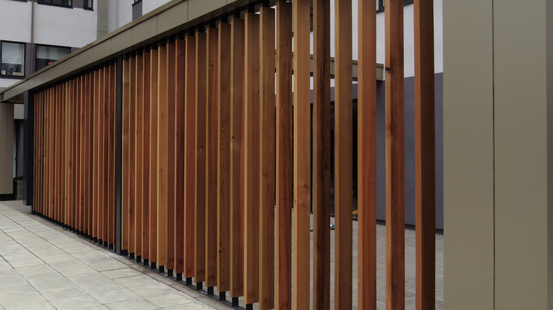 Metal sütunları ile dikey ahşap panjur çiti çerçeveleyen