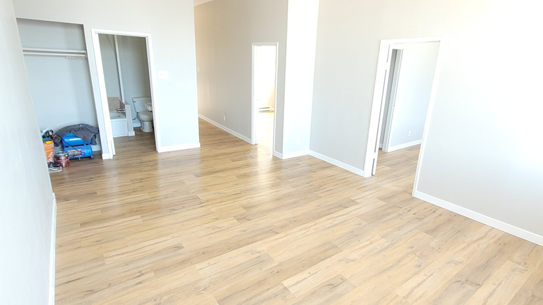 Beyaz duvarlı ve lüks vinil tahta döşeme ile boş bir yatak odası