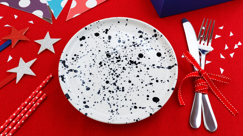 Şenlikli kırmızı, beyaz ve mavi dekore edilmiş masada Splatterware plakası