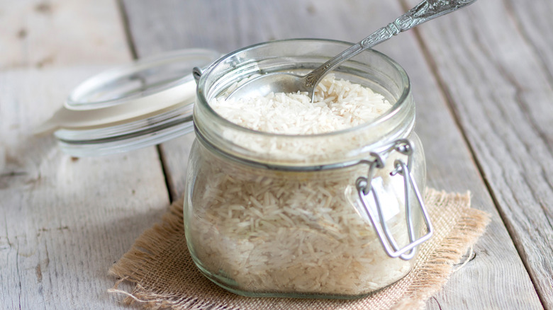 Üstte gümüş kaşıkla beyaz pirinç dolu açık cam kavanoz