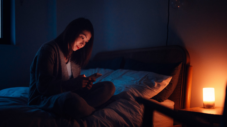 Kadın karanlık bir odada telefonuna bakıyor