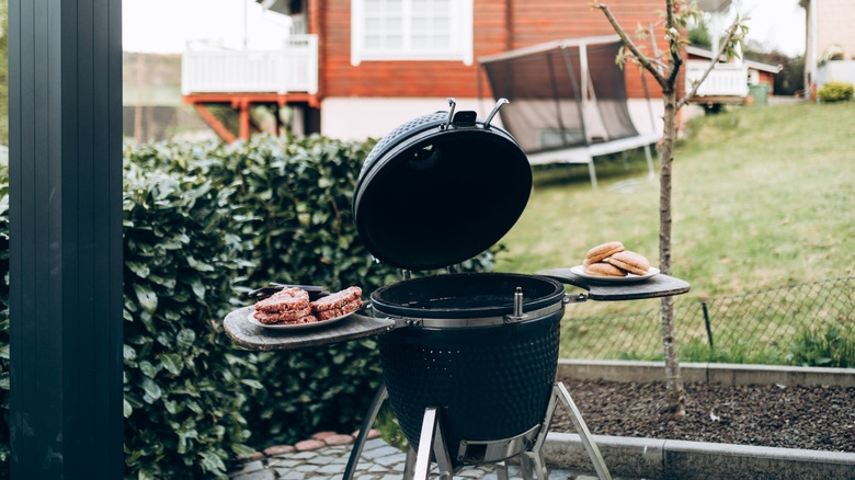 Bir tarafta hamburger ve diğer tarafta çörekler bulunan bir arka bahçede bir barbekü