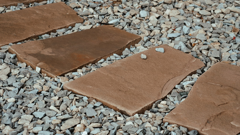 Bahçenin estetik çekiciliğini artıran küçük bir çakıl yatağına pürüzsüz doğal taş levhaların bir yolu döşenir.