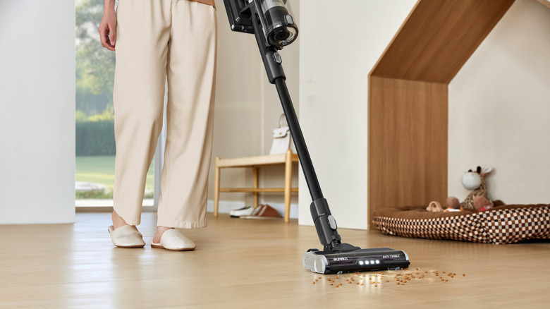 Eureka vakumu ile zeminden kırıntıları temizleyen bir kişi