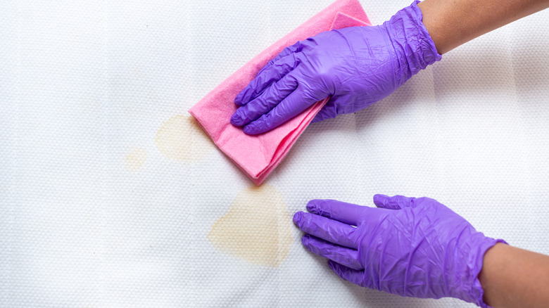 Bir yataktan leke temizleyen kişi