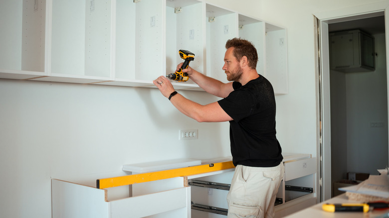 Mutfakta fab öncesi dolapları kuran bir adam.