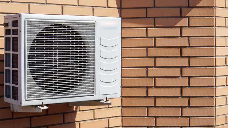 Modern bir iklim kontrol ünitesinin dışarıdaki bir evin cephesinin bir tuğla duvarının arka planına karşı yakın çekim atışı