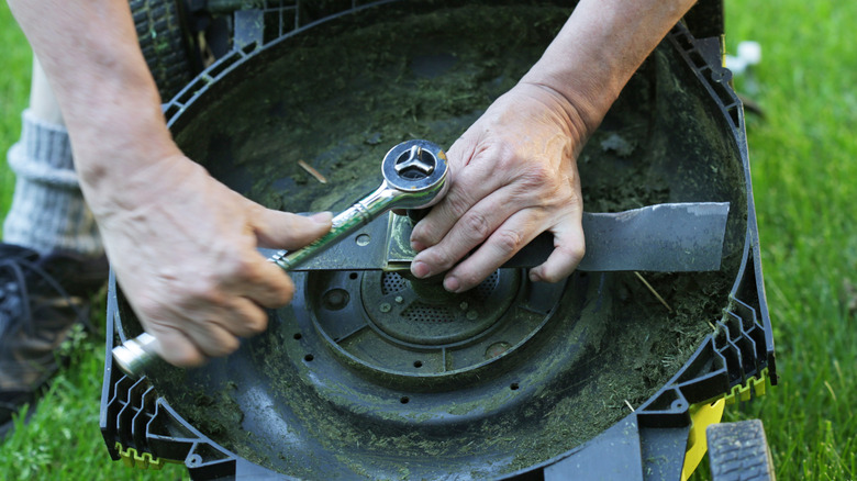 Çim biçme makinesi bıçağını değiştiren bir adam