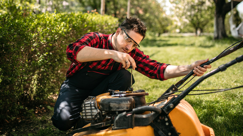 Birisi çim biçme makinesini denetleyen