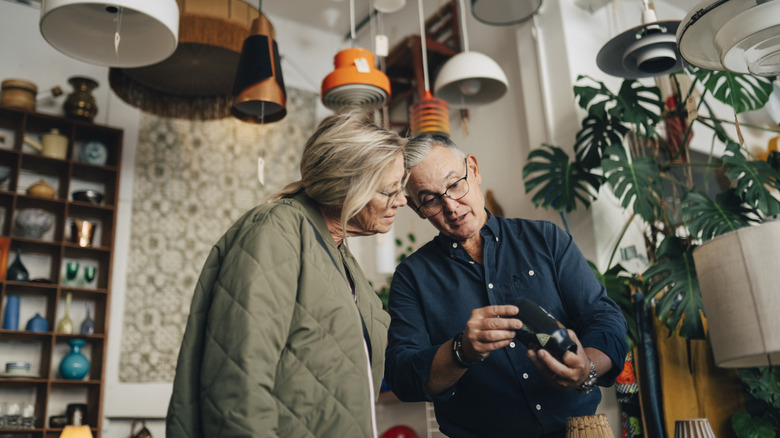 Bir dükkanda bir cam vazoya bakarak iki kişi