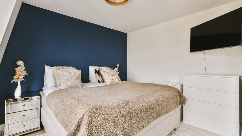 Kürklü yatağlı yatağın üstünde lacivert duvarı