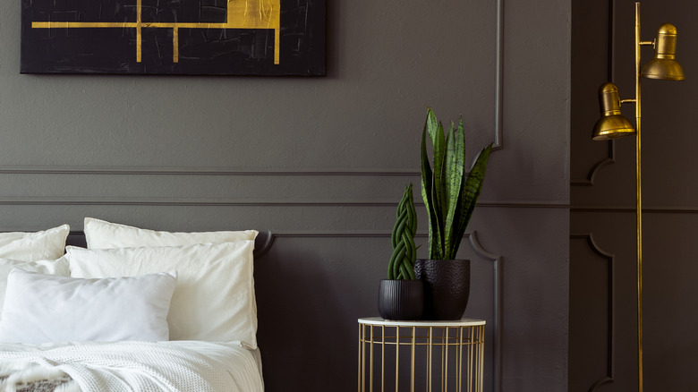 Beyaz yatak ve pirinç lamba ile kömür aksan duvarı