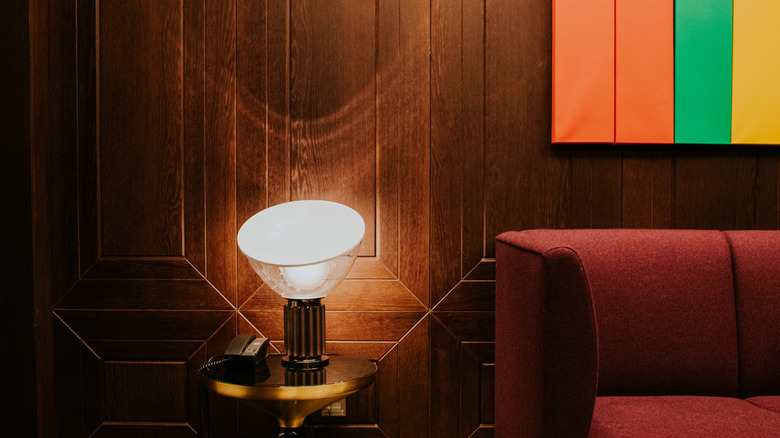 Bir kanepe ve uç masa, bir lamba ve telefonun arkasında odun panellerinin kapatılması