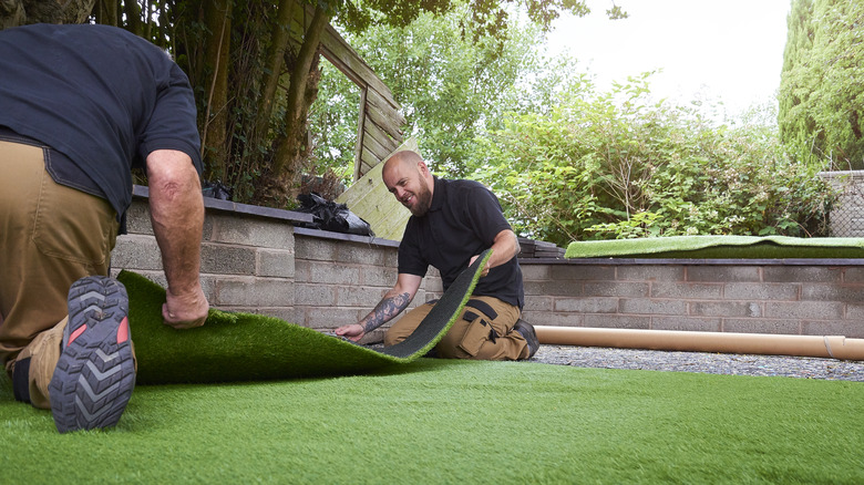 Bir bahçeye yapay çim takan erkekler