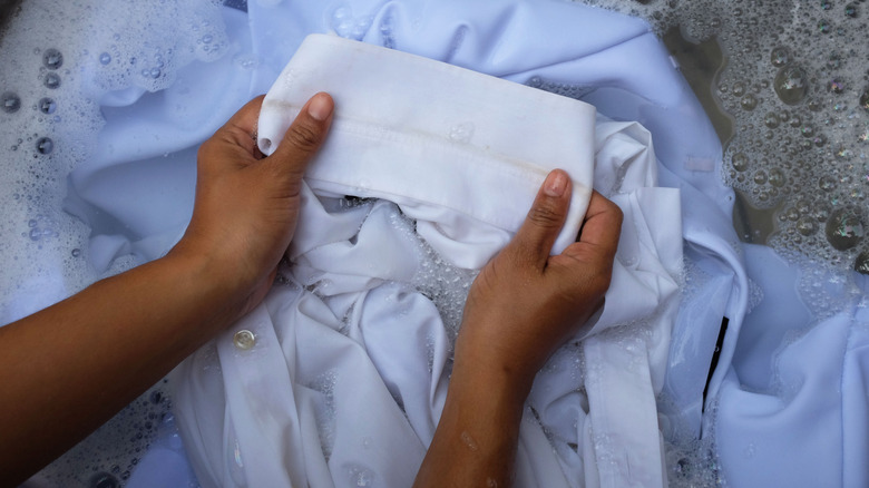 Suda kıyafetleri durulayan kişi