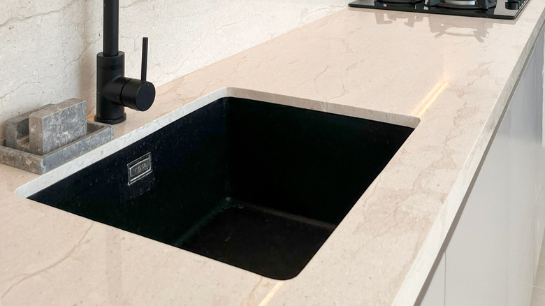 Tenarlanmış mermer backsplash ve siyah aletlerle mutfakta tezgah