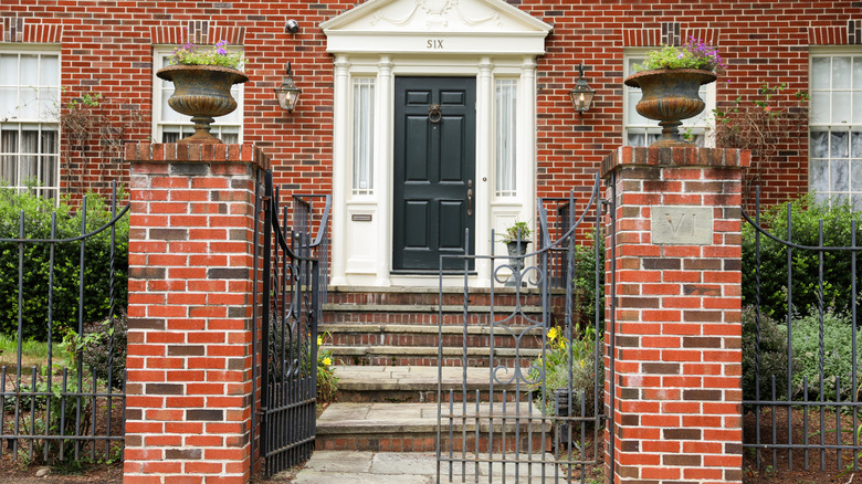 Bir ferforje çit ve kapı yakışıklı bir sömürge tuğlası evinin önünde