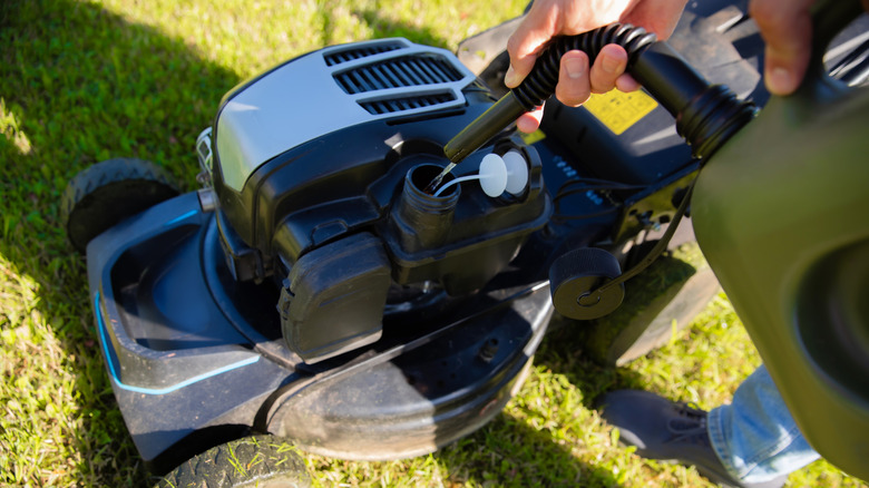 Bir çim biçme makinesine gaz ekleyen kişi