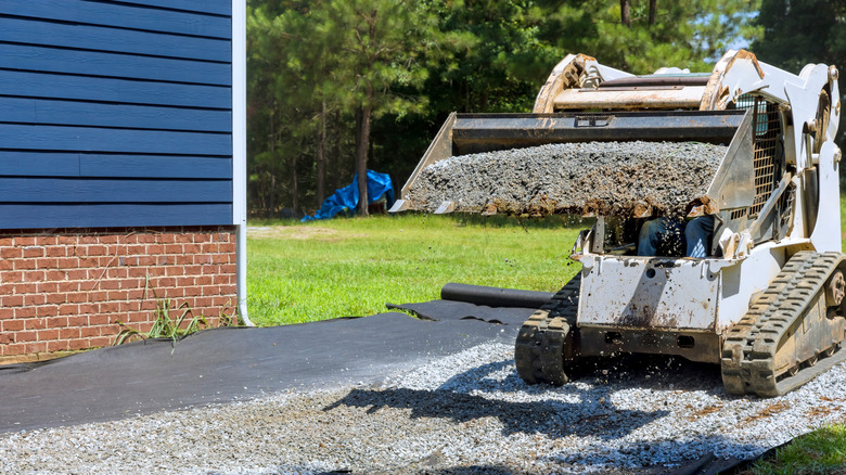 Traktör bir banliyö evinin önünde hareket eden çakıl