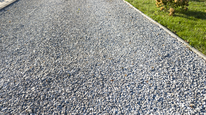 Yolun kenarındaki çimlerin yanında akan çakıl yolu