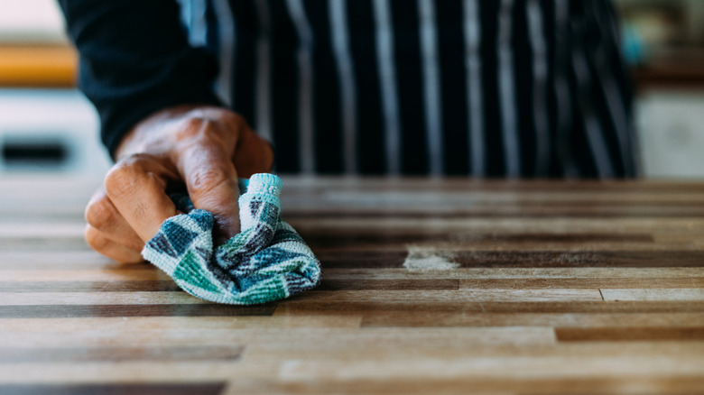 Kişi, yumuşak mavi havlu ile kasap bloğunu temizler