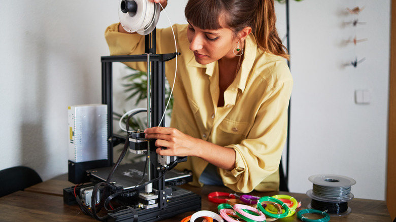 Bir kadın filamanı 3D yazıcıya yükler