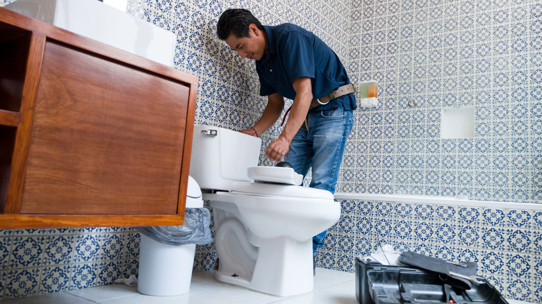 Banyoda tuvalet takan bir tesisatçı