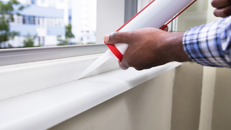 Bir kişi pencere çerçevesinin etrafına kalacakar