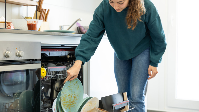 Bir kadın kirli bulaşıkları bulaşık makinesine yerleştirir