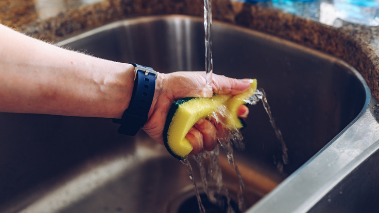 Bir süngeri ıslatan bir kişinin yakından