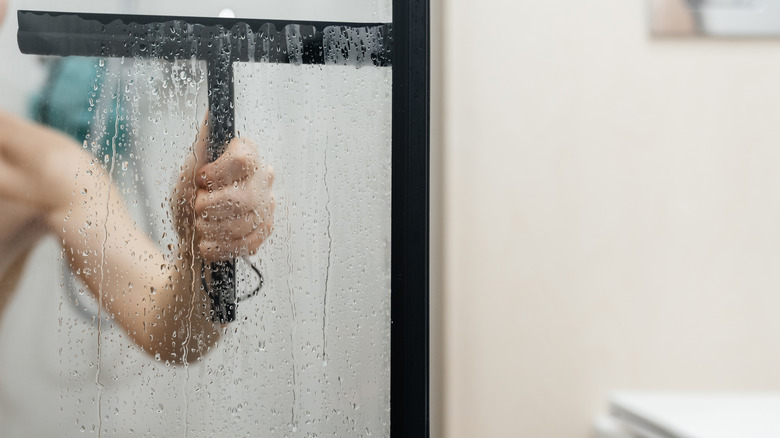 Duş camını temizlemek için bir Squegee kullanarak elin kapatılması