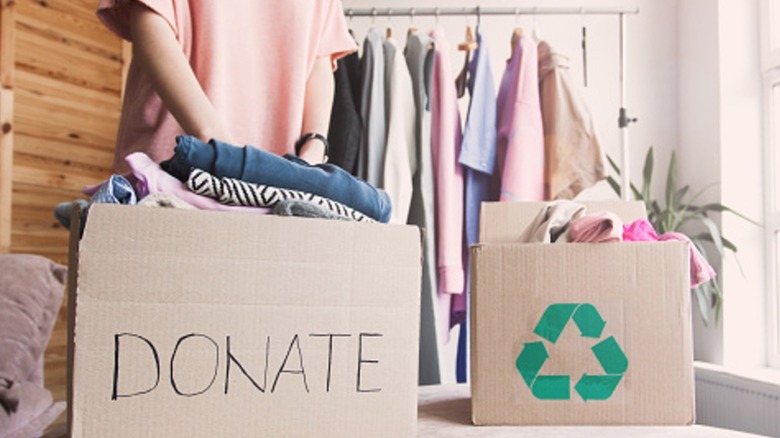 Bağış için bir kutuya kıyafetler paketleyen kişi