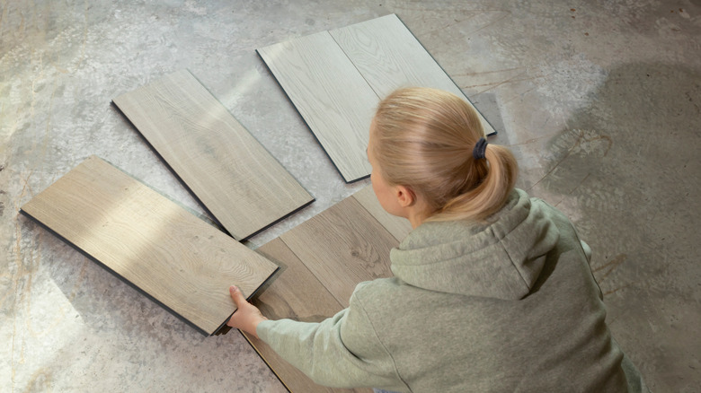 Zemine karşı çeşitli renk vinil döşeme örnekleri tutan kadın