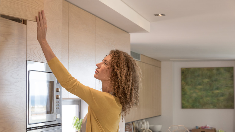 Mutfağında vinil sarılmış bir dolap kapatan bir kadın.