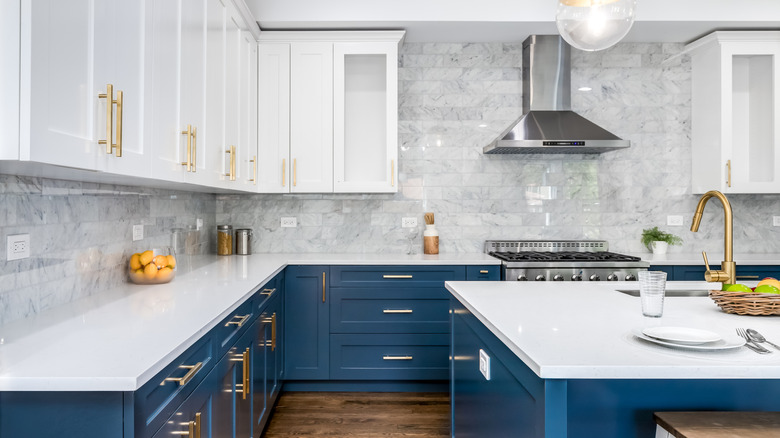 Koyu mavi alt dolaplar ve mutfak adası ve beyaz üst dolapları ile lüks mutfak alanı