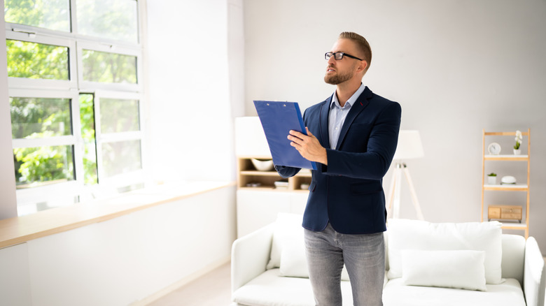 Bir adam bir evi değerlendirirken bir pano tutar