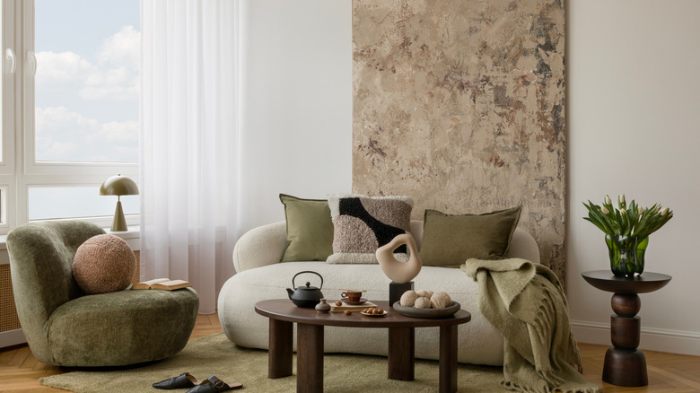 Çeşitli kumaş dokuları ve beyaz ve yeşil mobilyalı nötr oturma odası