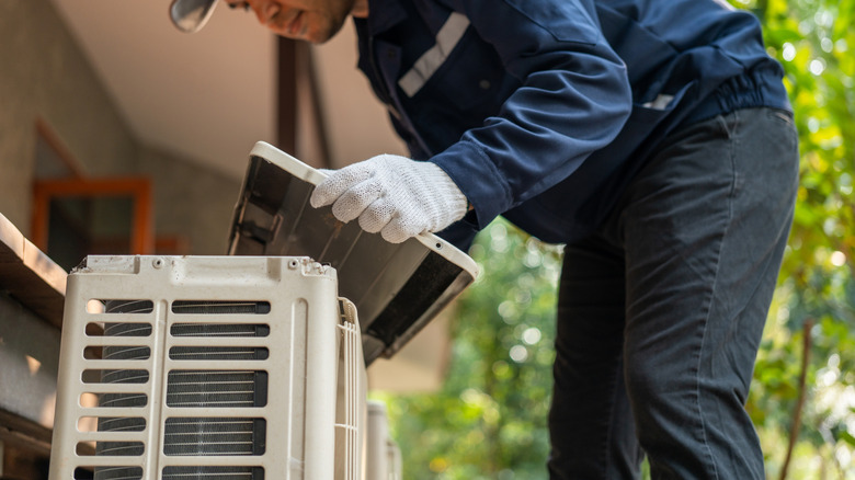 Açık hava AC ünitesine örtü yerleştiren bir klima teknisyeni