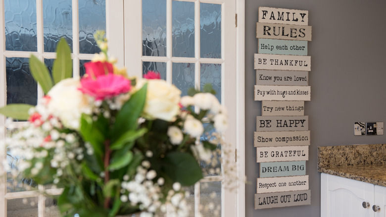 Bir evin içinde taze kesilmiş çiçekler vazo ile bir mutfakta bir duvarda asılı çeşitli sözler ve alıntılar ile bir işaretin genel bir görünümü.