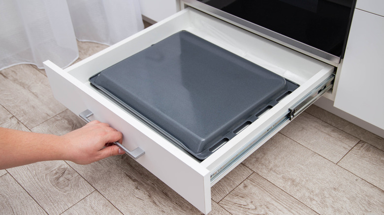 Çerez tabakaları ile fırın çekmecesini çeken el