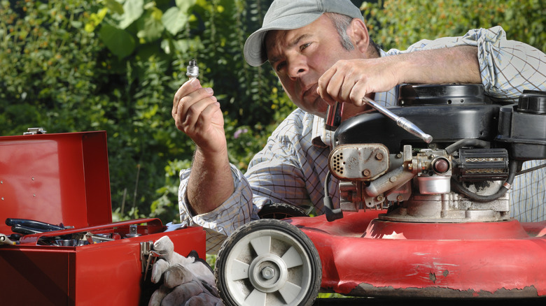 Çim biçme makinesini tamir eden bir adam