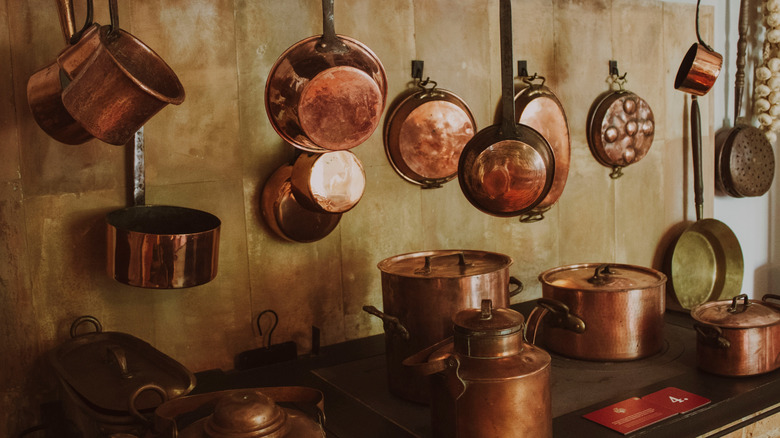 Bir sobanın üzerinde asılı asılı antika bakır kaplar ve tavalar.