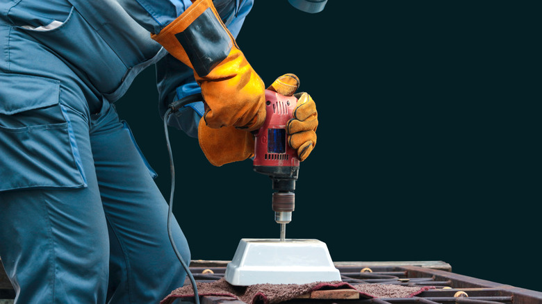 Güvenlik ekipmanı ile küçük bir seramik tencereye bir delik açan biri