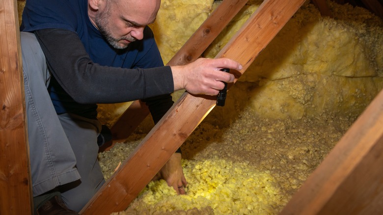 Ahşap çatı iç yapısını inceleyen bir ev müfettişi