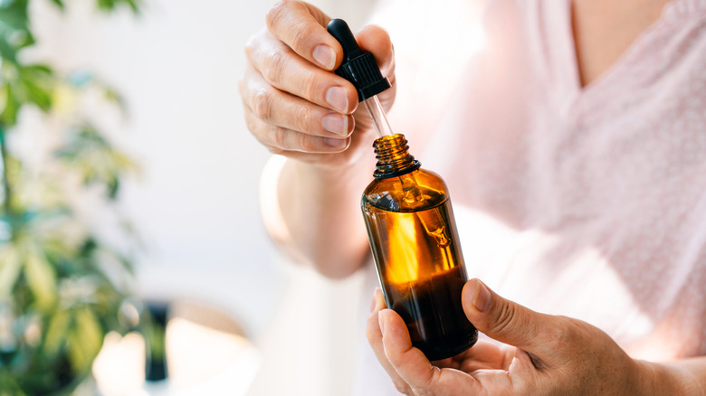 Kişi, küf kokularını çamaşırlarından çıkarmak için çam esansiyel yağı ölçer.