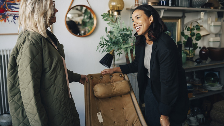 Bir mağazada deri döşemeli bir sandalyeyi tartışan iki kişi